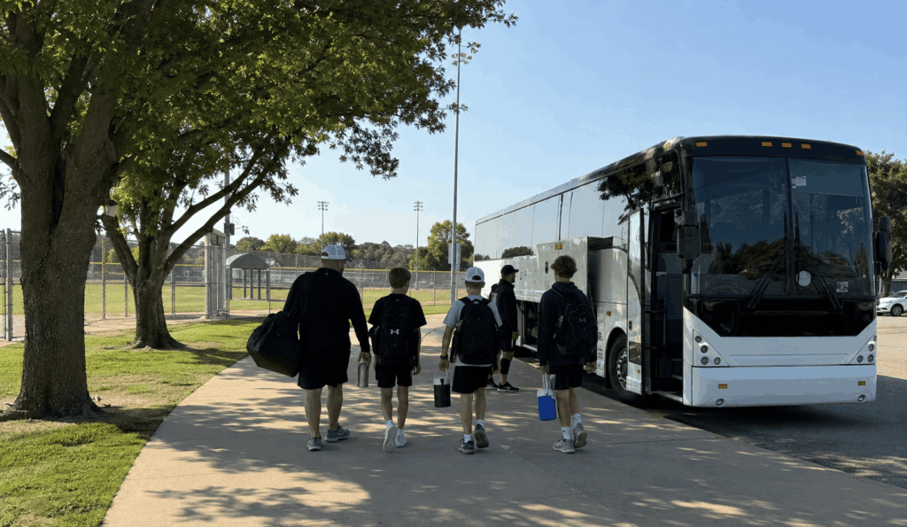 youth sports team boarding a charter bus at a fort worth practice field before a tournament trip