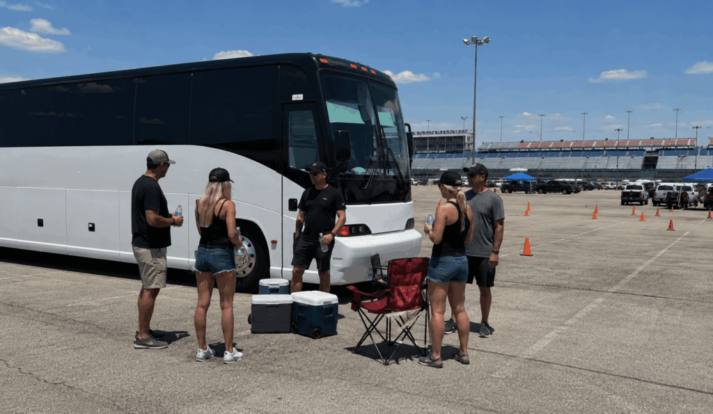race fans relaxing beside a charter bus before an event at texas motor speedway